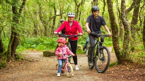 Family exploring the cycle trails at Lanhydrock, Cornwall surrounded by trees and woodland